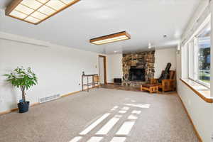 Basement living room with light carpet and a stone fireplace