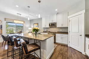 Kitchen featuring a kitchen bar, pendant lighting, dark hardwood / wood-style floors, and appliances with stainless steel finishes