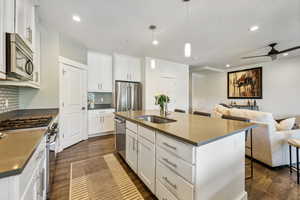 Kitchen featuring pendant lighting, stainless steel appliances, a kitchen island with sink, and sink