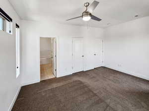 Unfurnished bedroom with light colored carpet, ensuite bath, and ceiling fan