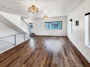 Unfurnished living room with wood-type flooring and a chandelier