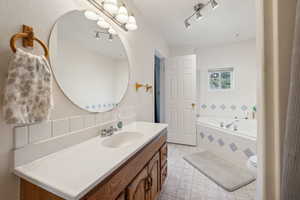 Bathroom featuring vanity, toilet, and a relaxing tiled tub