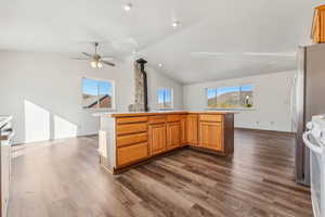 Kitchen with lofted ceiling, ceiling fan, a wood stove, dark wood-type flooring, and white electric range