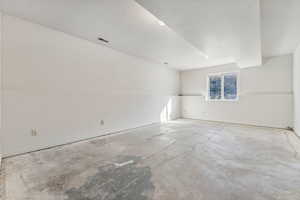 Empty room featuring vaulted ceiling and concrete floors