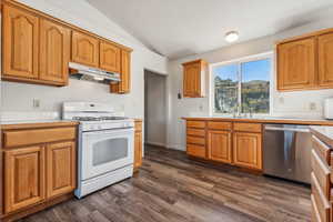 Kitchen with lofted ceiling, sink, dishwasher, white range with gas stovetop, and dark hardwood / wood-style flooring