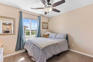 Carpeted bedroom featuring ceiling fan