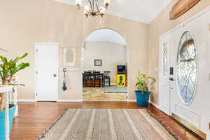 Foyer with vaulted ceiling, ornamental molding, a notable chandelier, and light hardwood / wood-style flooring