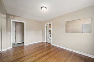 Spare room featuring wood-type flooring and a textured ceiling