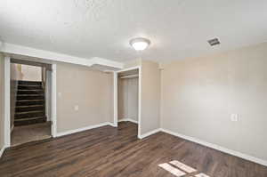 Unfurnished bedroom with dark wood-type flooring, a textured ceiling, and a closet