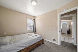 Bedroom featuring carpet, a textured ceiling, and white fridge