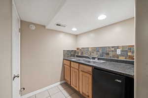 Kitchen featuring a textured ceiling, dishwasher, light tile patterned floors, tasteful backsplash, and sink