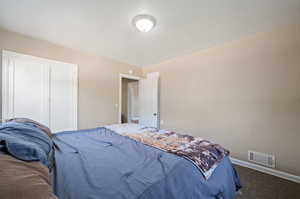 Bedroom featuring dark carpet and a textured ceiling