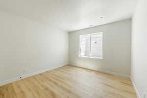 Bedroom with a textured ceiling and light hardwood / wood-style flooring. 2411 S.