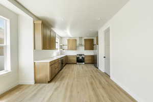 Kitchen with stainless steel appliances, tasteful backsplash, wall chimney exhaust hood, and light hardwood / wood-style floors. 2411 S.