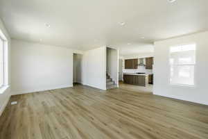 Living room with light wood-type flooring and kitchen in the background. 2425 S.