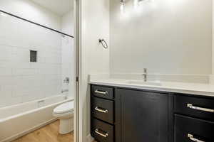 Full bathroom featuring hardwood / wood-style floors, tiled shower / bath, toilet, and vanity. 2425 S.