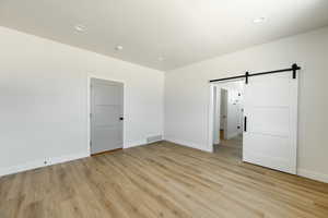 Owner's Suite with a barn door and light hardwood / wood-style floors. 2425 S.