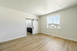 Owner's Suite features a barn door, light wood-type flooring, and a textured ceiling. 2425 S.