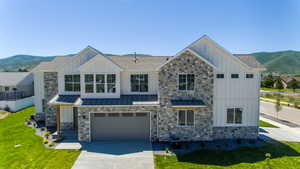 View of front of house featuring a mountain view, central air condition unit, a garage, and a front lawn.