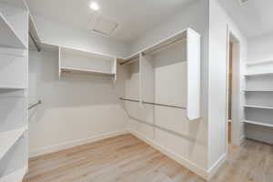 Spacious Owner's closet with light hardwood / wood-style flooring. 2411 S.