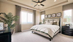 Carpeted bedroom with a tray ceiling and ceiling fan