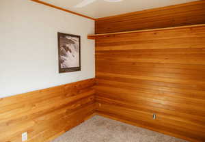 Carpeted empty room with crown molding and wood walls