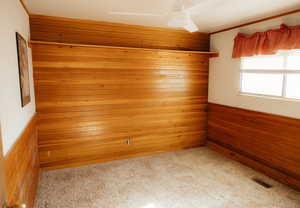 Carpeted empty room featuring wood walls