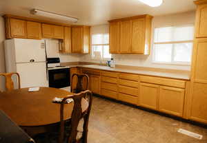 Kitchen with white appliances, plenty of natural light, and sink