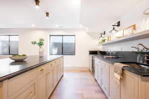 Kitchen with cream cabinets, light hardwood / wood-style flooring, beverage cooler, and sink