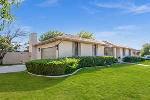 Ranch-style house featuring a garage and a front lawn