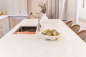 Kitchen with light stone countertops, a breakfast bar area, sink, and high end fridge