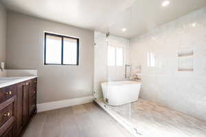 Bathroom with tile walls, shower with separate bathtub, tile patterned floors, and vanity