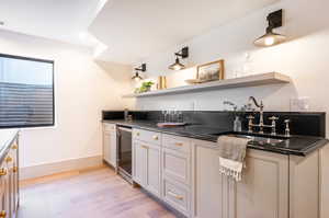 Kitchen featuring wine cooler, light hardwood / wood-style floors, and sink