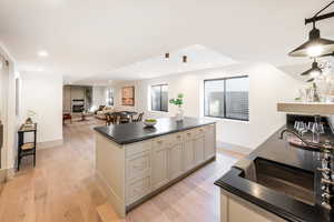 Kitchen featuring light wood-type flooring, a center island, and a fireplace