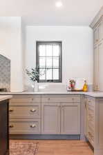 Kitchen featuring gray cabinets, decorative backsplash, and light wood-type flooring