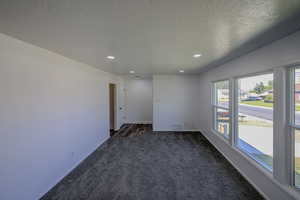 Empty room featuring a textured ceiling and dark colored carpet