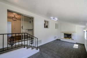 Interior space with a fireplace, a textured ceiling, and a notable chandelier