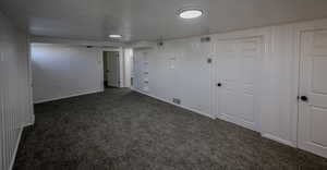 Basement with dark colored carpet and a textured ceiling