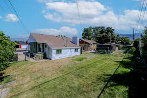 Rear view of property featuring a mountain view and a lawn