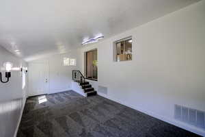 Carpeted foyer featuring lofted ceiling and a textured ceiling