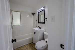 Full bathroom with tile patterned floors, tiled shower / bath, toilet, and vanity