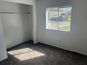 Unfurnished bedroom featuring dark carpet and a closet