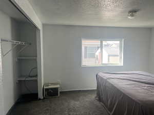 Bedroom with dark colored carpet and a textured ceiling