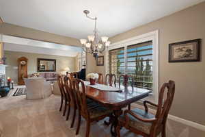 Carpeted dining room with a chandelier