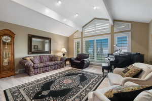 Carpeted living room with vaulted ceiling with beams