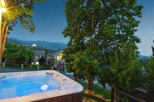 Pool at dusk with a mountain view and a hot tub