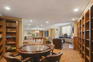 Carpeted dining room with a textured ceiling and pool table