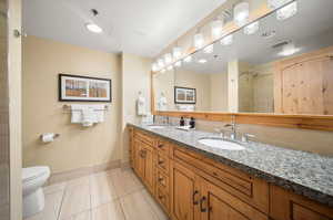 Bathroom with tile patterned flooring, toilet, a tile shower, and vanity