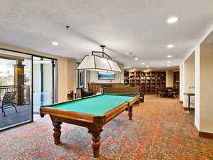 Recreation room with a textured ceiling, carpet, and pool table