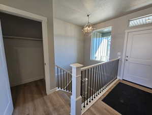 Foyer featuring dark wood-type flooring, a textured ceiling, and an inviting chandelier